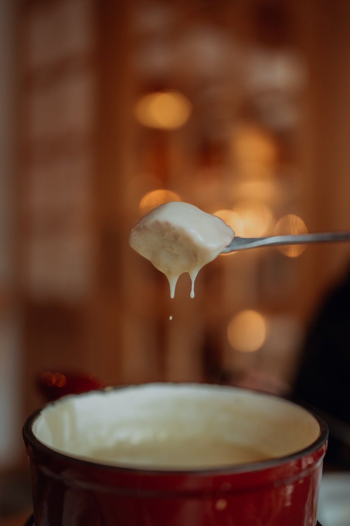 Käsefondue: Brotwürfel mit geschmolzenem Käse über dem Caquelon