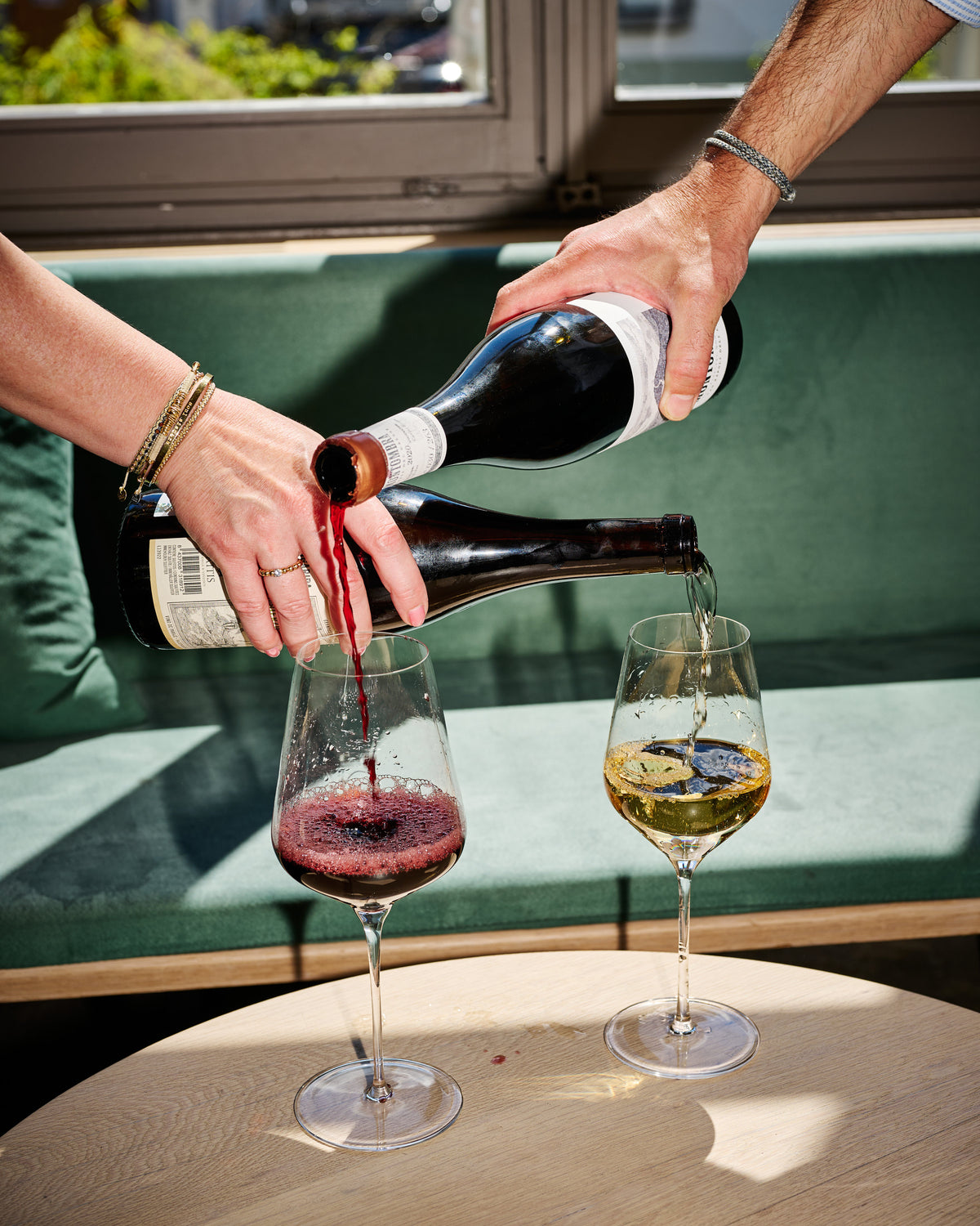 Rotwein und Weisswein werden gleichzeitig in zwei Gläser eingeschenkt